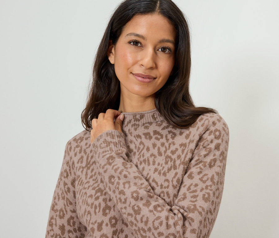 Frau mit dunklen, langen Haaren trägt einen hellbraunen Pullover mit Leopardenmuster.