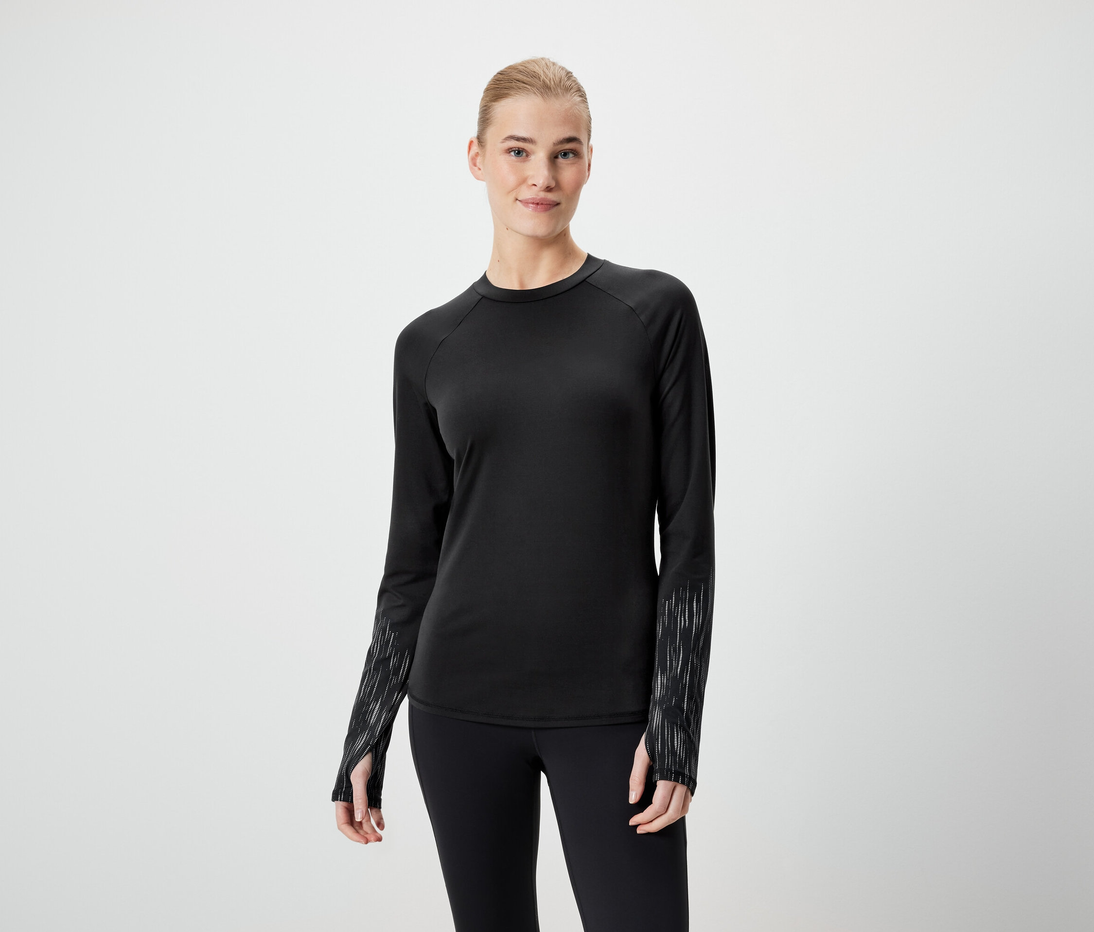 Frau trägt ein schwarzes Langarmshirt und schwarze Leggings.