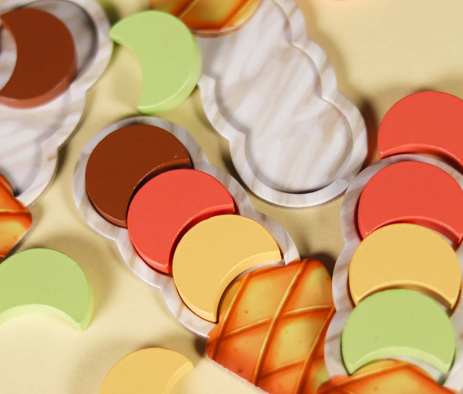 Nahaufnahme des Spiels »Carla Caramel« mit hölzernen Eiskugeln auf Papierwaffeln.