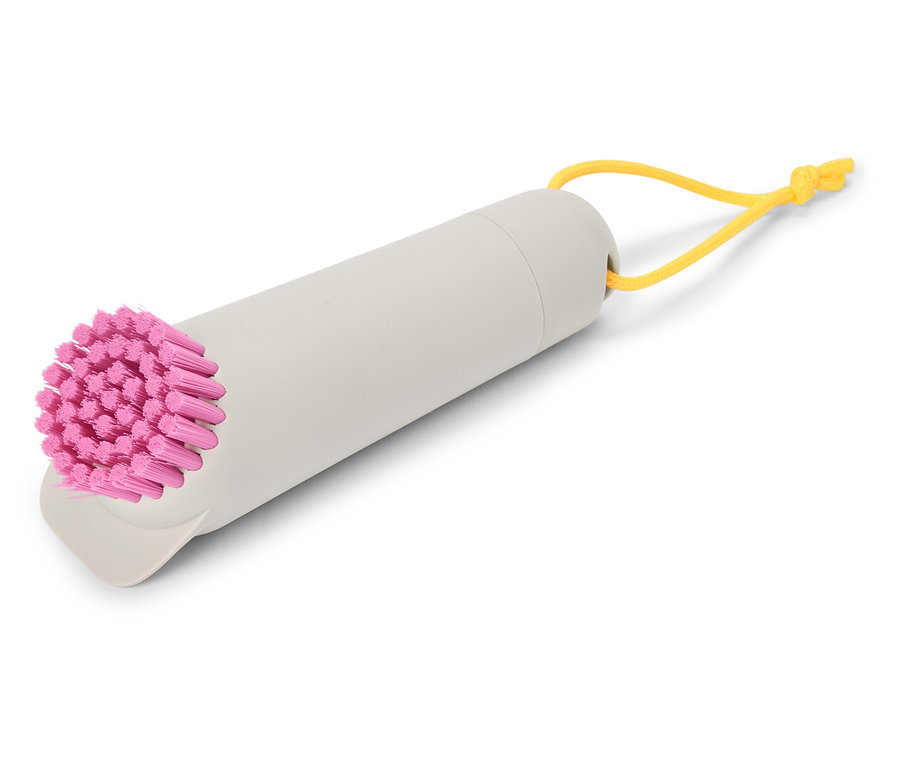 Eine graue Bürste mit pinkfarbenen Borsten und einer gelben Schlaufe liegt auf einem weißen Hintergrund.
