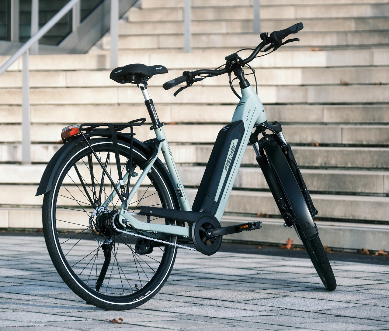 Ein Fischer City E-Bike CITA 2403 ACTIVE, 50 cm steht vor einer Treppe.