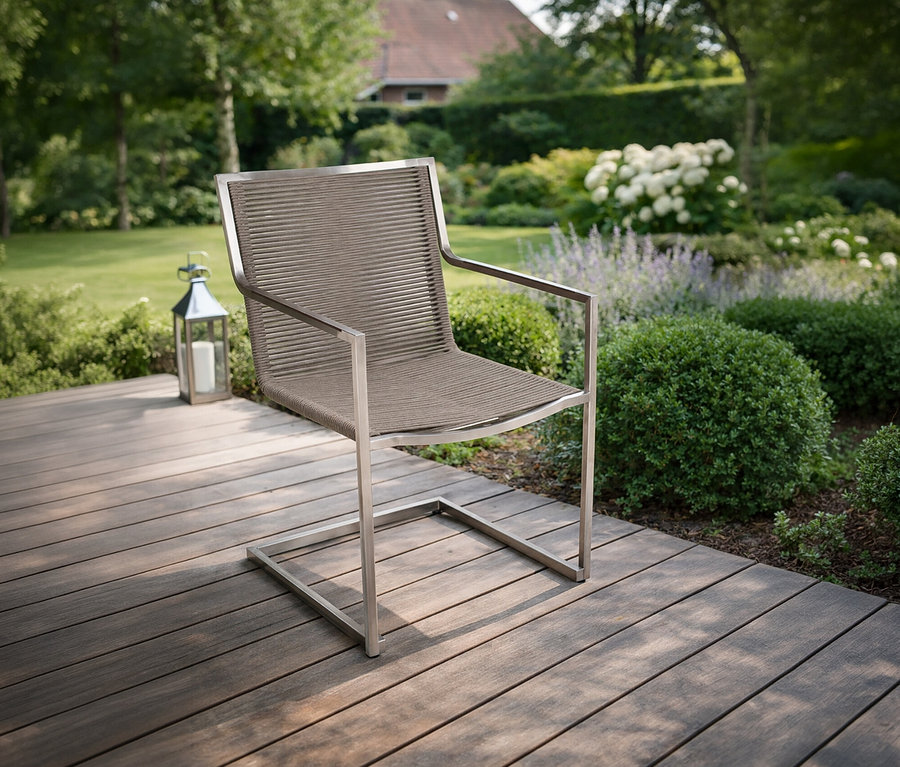 Ein »Sienna« Freischwinger steht auf einer Holzterrasse vor einem Garten.