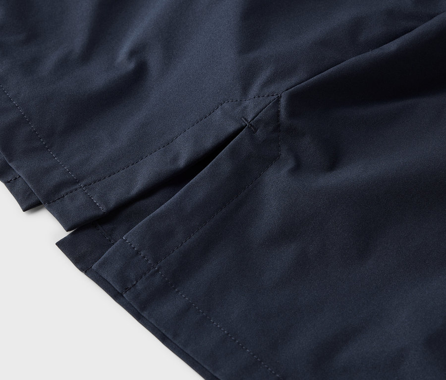 Nahaufnahme von marineblauen Shorts mit seitlichem Schlitz und grauen Nähten auf weißem Hintergrund.
