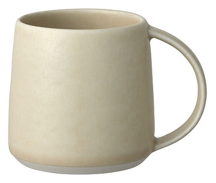 Eine einzelne, hellbeige Keramiktasse mit Henkel steht vor einem weißen Hintergrund.
