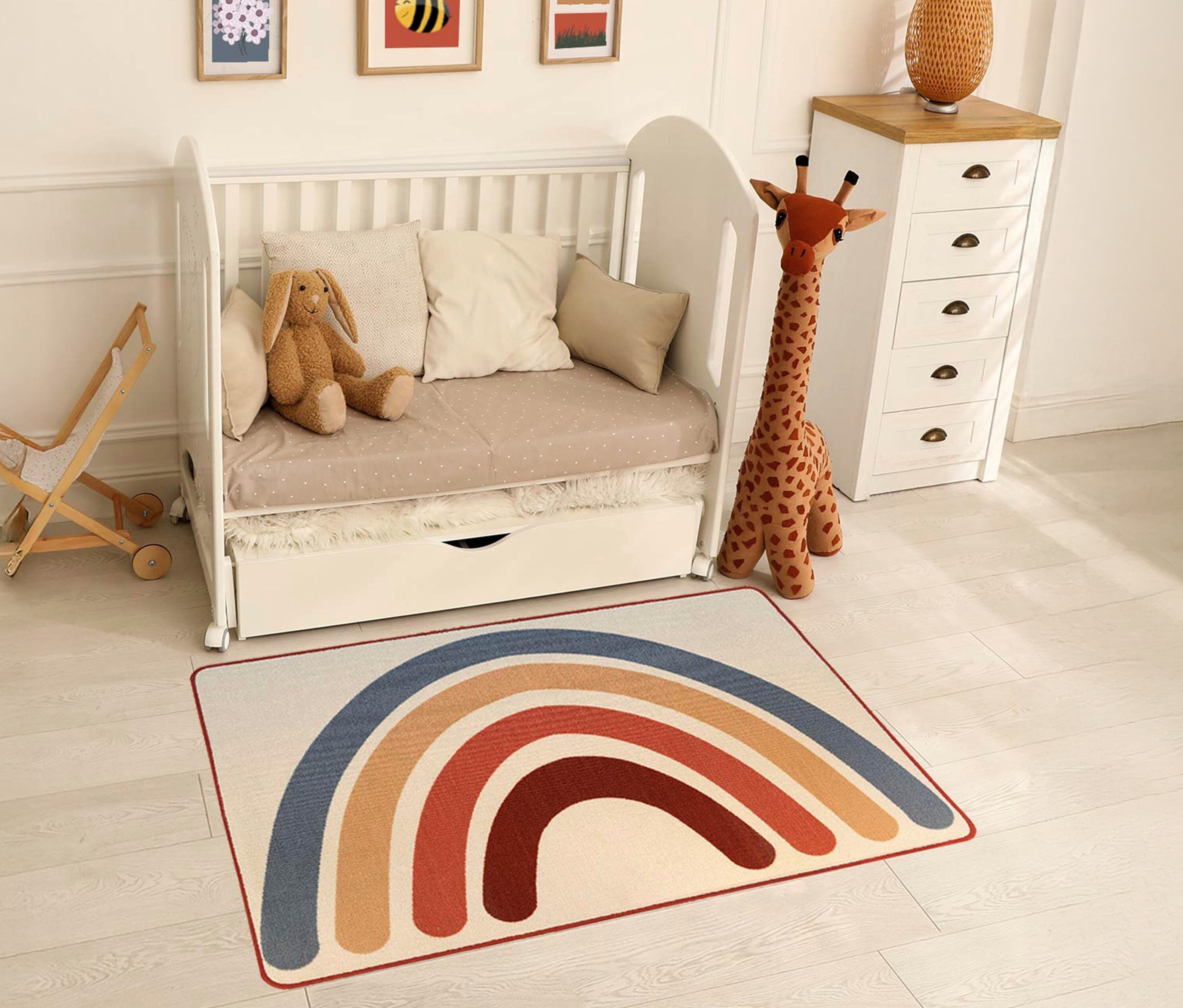 Ein Kinderzimmer mit einem weißen Kinderbett, einer Spielzeuggiraffe und einem »Rainbow« Kinderteppich im Vintage-Stil.