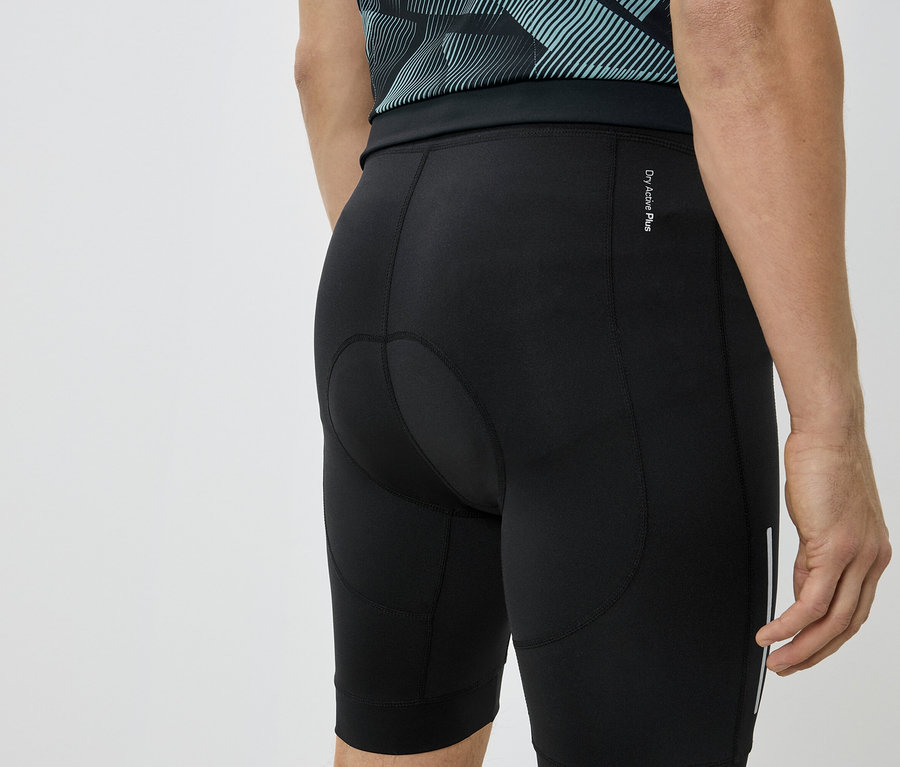 Nahaufnahme der Rückseite einer Person, die schwarze Radlerhosen und ein blaugrünes Shirt trägt.