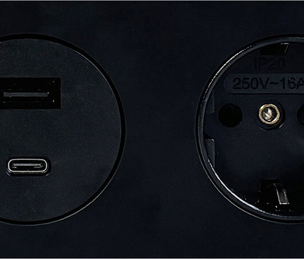 Nahaufnahme einer schwarzen Steckdose mit USB- und USB-C-Anschlüssen.