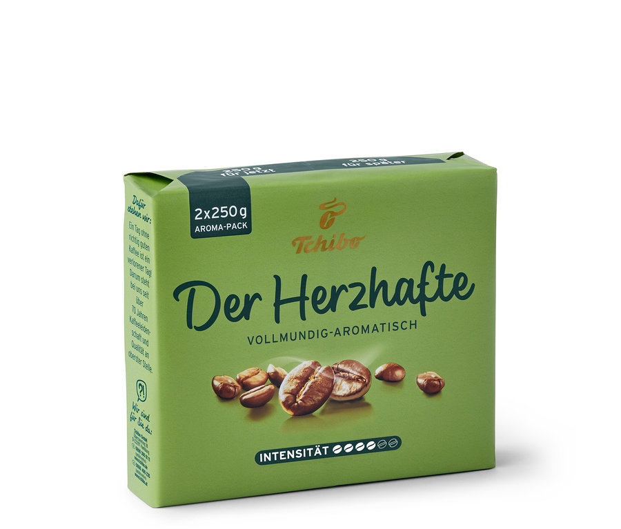 Eine grüne Packung 'Der Herzhafte' Kaffee von Tchibo mit Kaffeebohnen und Intensitätsanzeige.