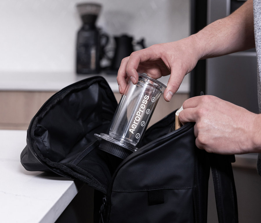 Mann legt eine transparente AeroPress Coffee Maker in eine schwarze Tasche.