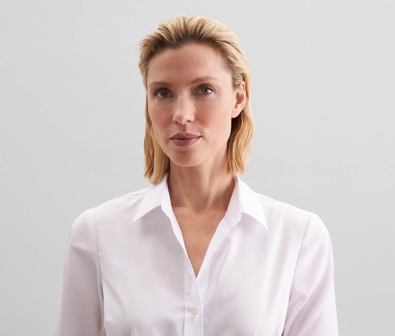 Frau mit blondem Haar trägt eine weiße Seidensticker Bluse Slim Fit non iron.