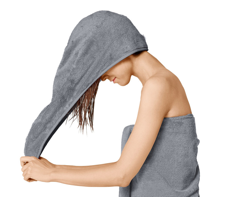 Frau wickelt ein Turban-Handtuch um ihr nasses Haar.
