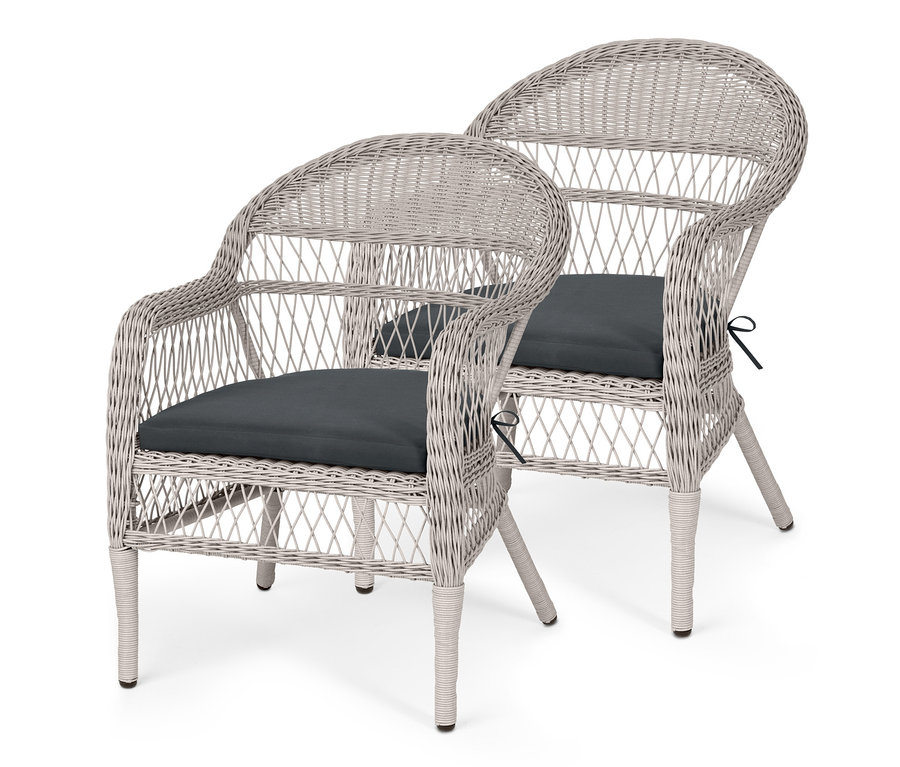 Zwei Gartensessel aus Polyrattan mit dunklen Sitzkissen.