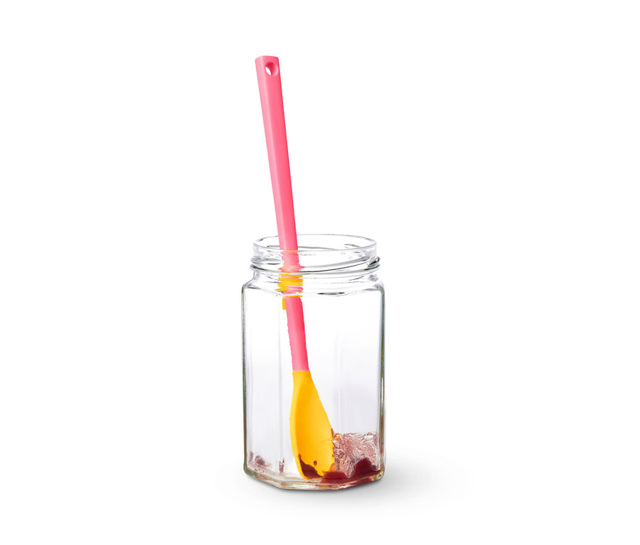 Ein Spezial-Silikonlöffel steht in einem transparenten Glas mit Marmelade.