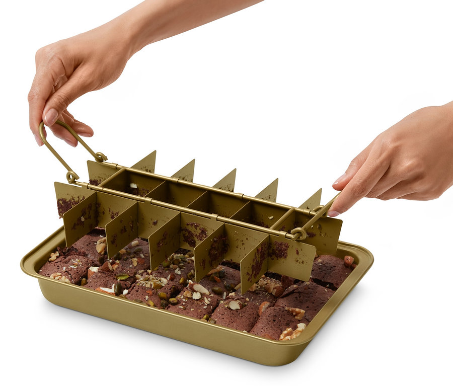 Eine Person hält eine Brownie-Backform über einem Backblech mit geschnittenen Brownies.