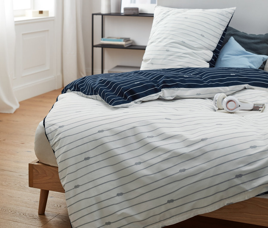 Perkal-Bettwäsche Normalgröße mit blauen Streifen und Knotenmuster auf einem Bett.