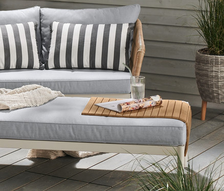 Ausklappbarer Tisch Liska mit grauem Schalenstuhl aus recyceltem Kunststoff. Outdoor-Sofa Liska mit Teak-Sofatablett mit flexiblen Lamellen.