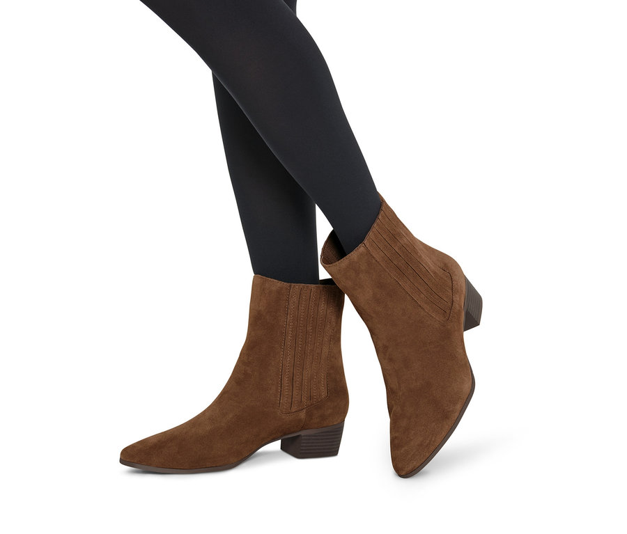Beine in schwarzen Strumpfhosen, bekleidet mit braunen Stiefeletten aus Veloursleder.