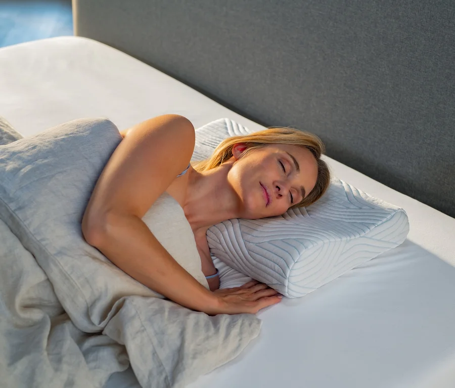 Frau schläft auf TEMPUR® Shape Queen SmartCool™ Schlafkissen auf einem weißen Bettlaken.