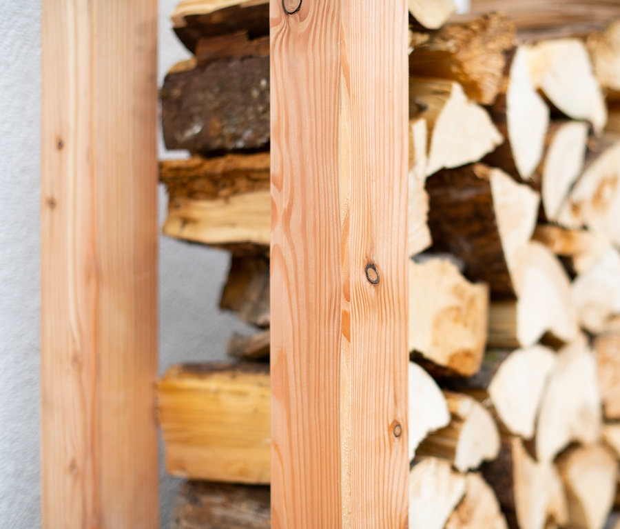 Holzscheite sind in einem Kaminholzständer, L, gestapelt.