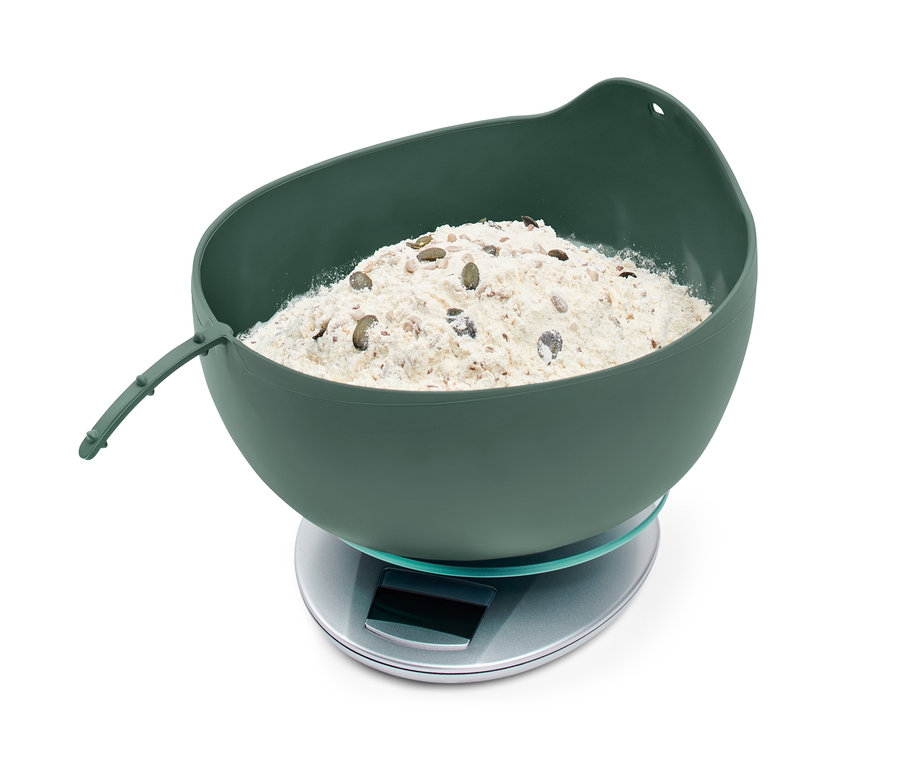 Eine grüne Brotbackschale mit Teig auf einer Waage.