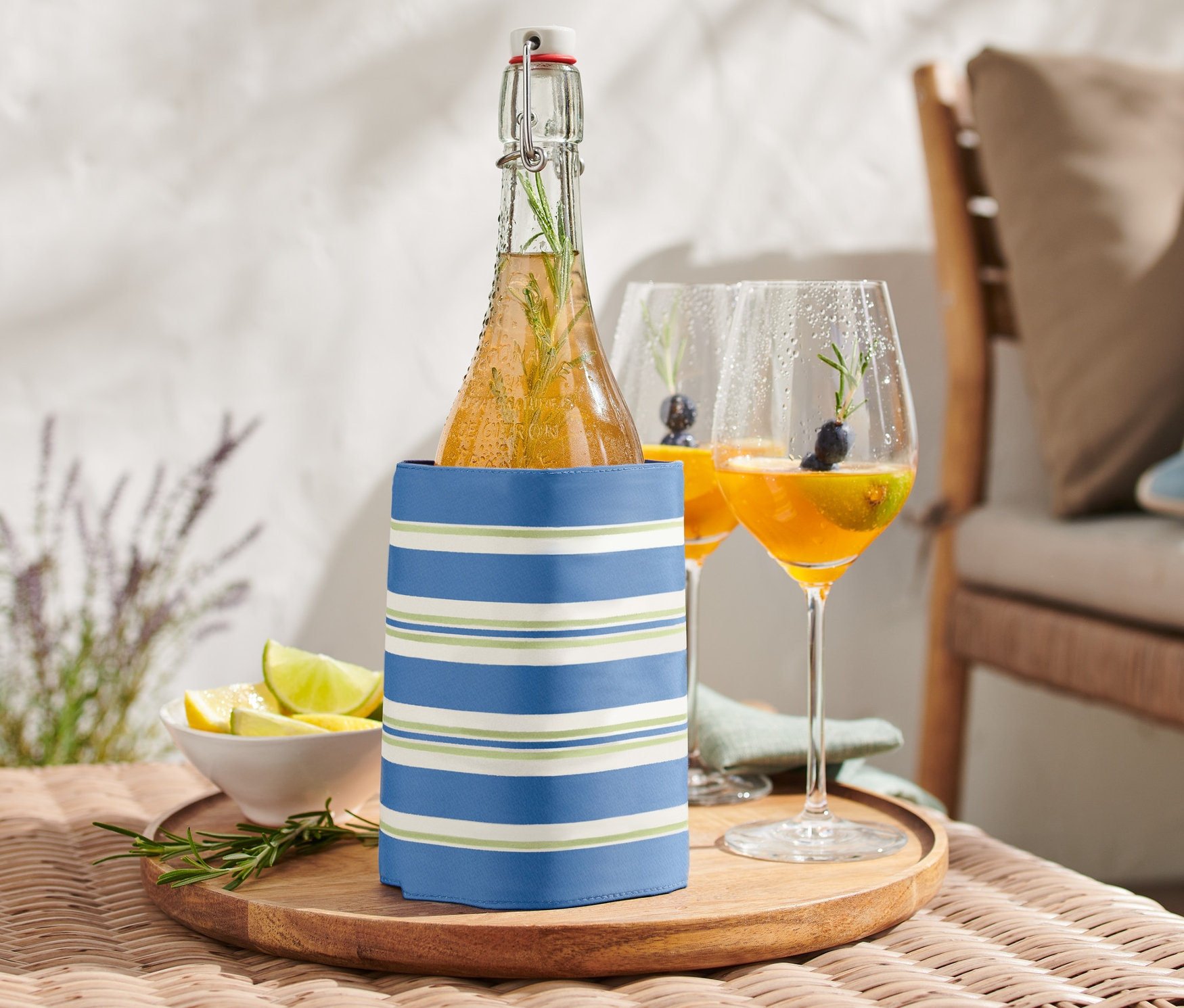Flasche in Flaschen-Kühlmanschette auf einem Tisch neben zwei Getränkegläsern.
