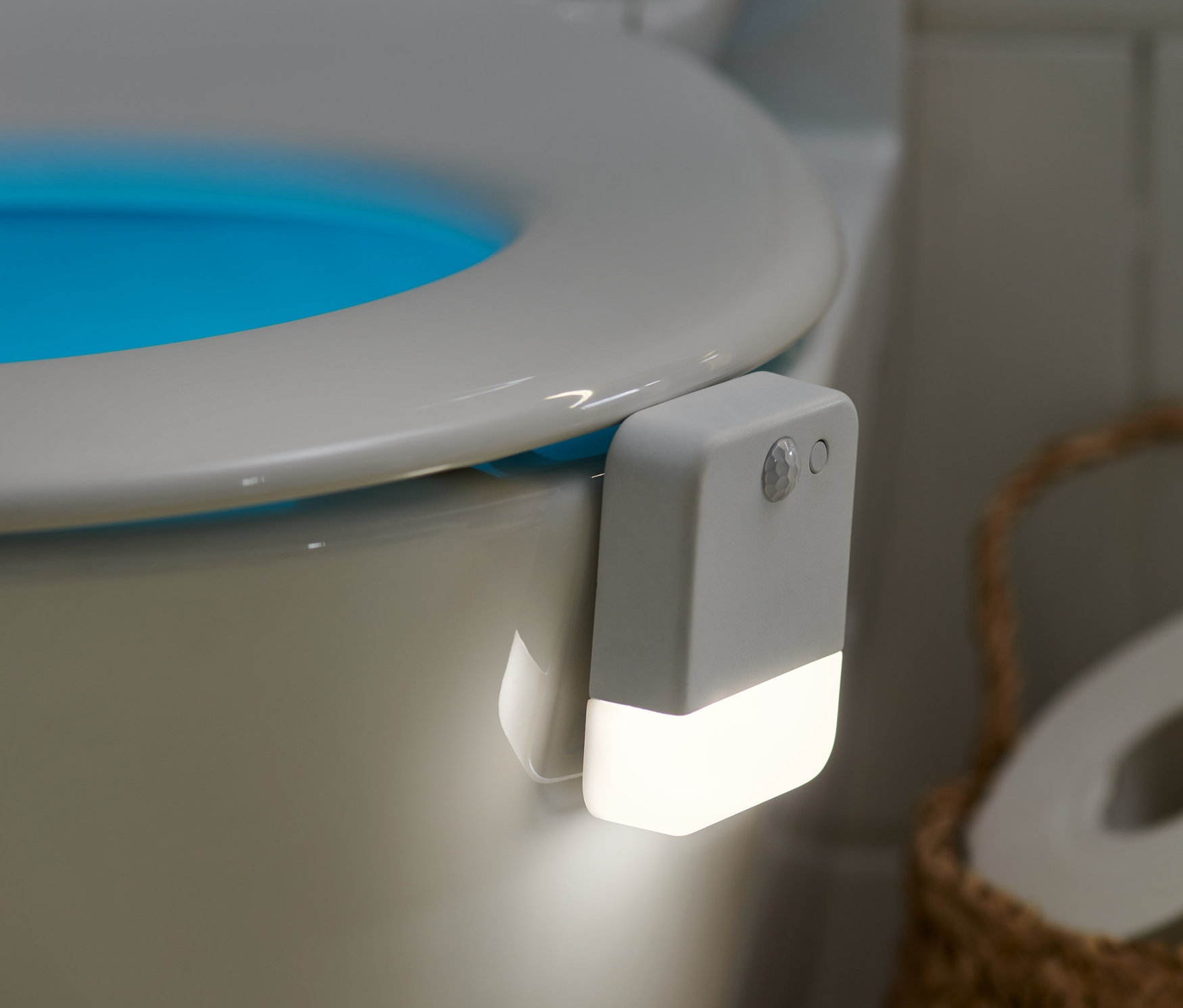 Ein LED-Toilettennachtlicht mit Bewegungsmelder ist an einer Toilette installiert und beleuchtet die Innenseite der Schüssel blau.