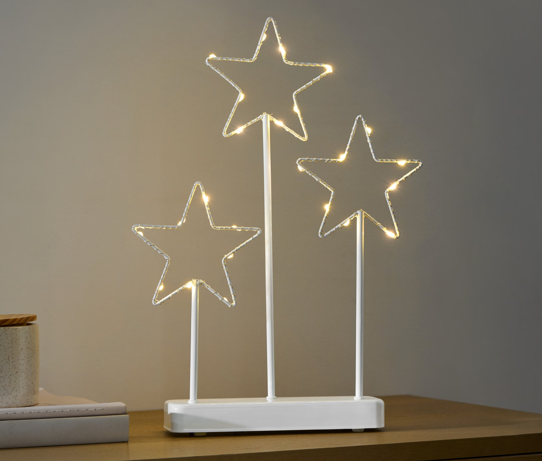 Drei stehende LED-Sterne auf einer Kommode.