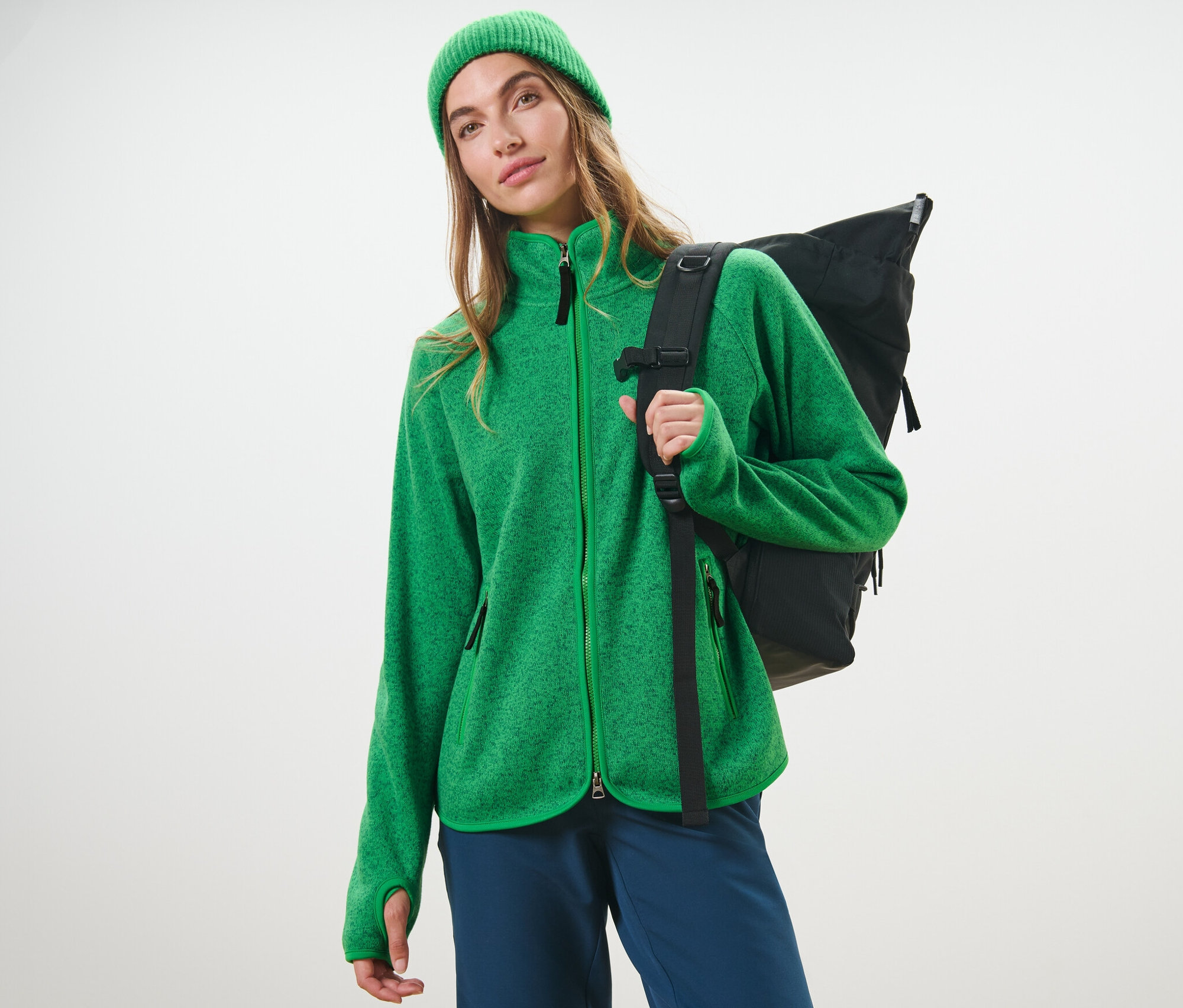 Frau trägt eine grüne Strickfleece-Jacke und einen schwarzen Rucksack.