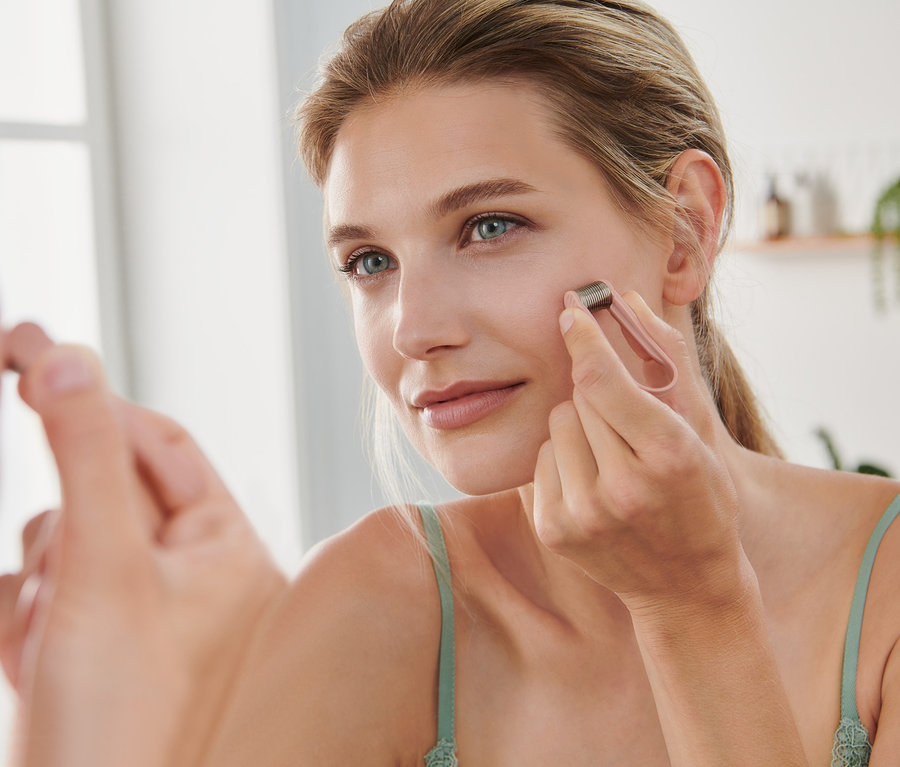 Frau verwendet Mini-Gesichtshaarentferner vor dem Spiegel.
