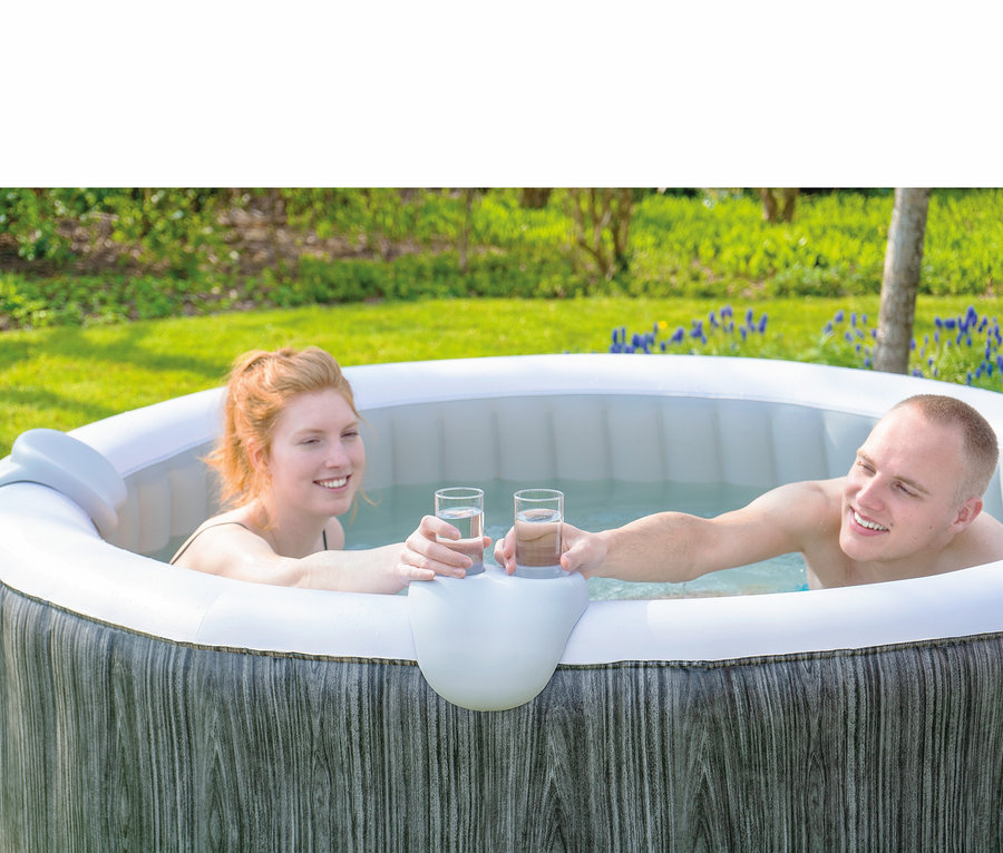 Zwei Personen stoßen mit Gläsern im EXIT Wood Deluxe Whirlpool für 4 Personen an.