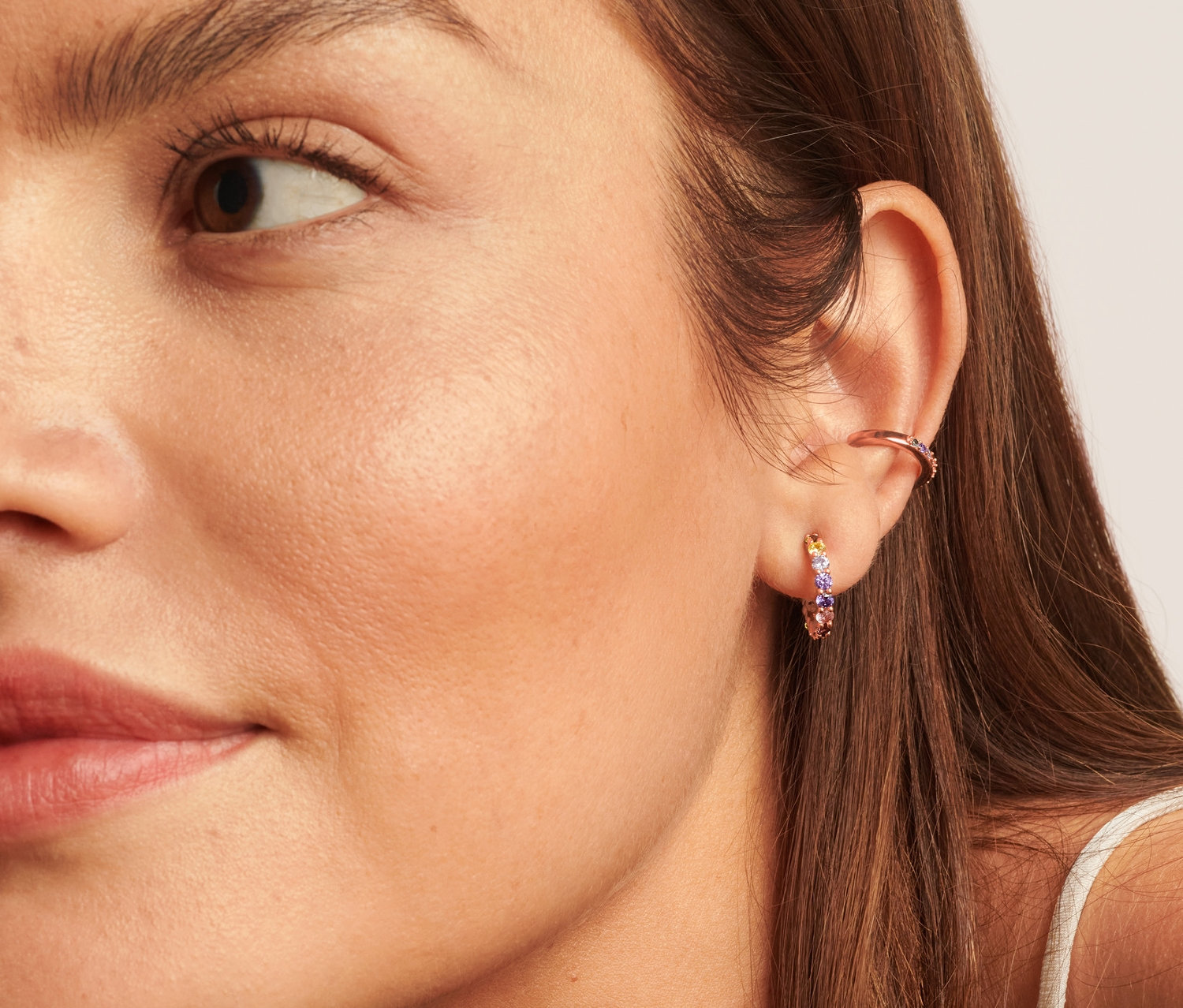 Detailaufnahme vom Gesicht einer Frau, die mehrfarbige 925 Silber Creolen und einen 925 Silber Earcuff trägt.