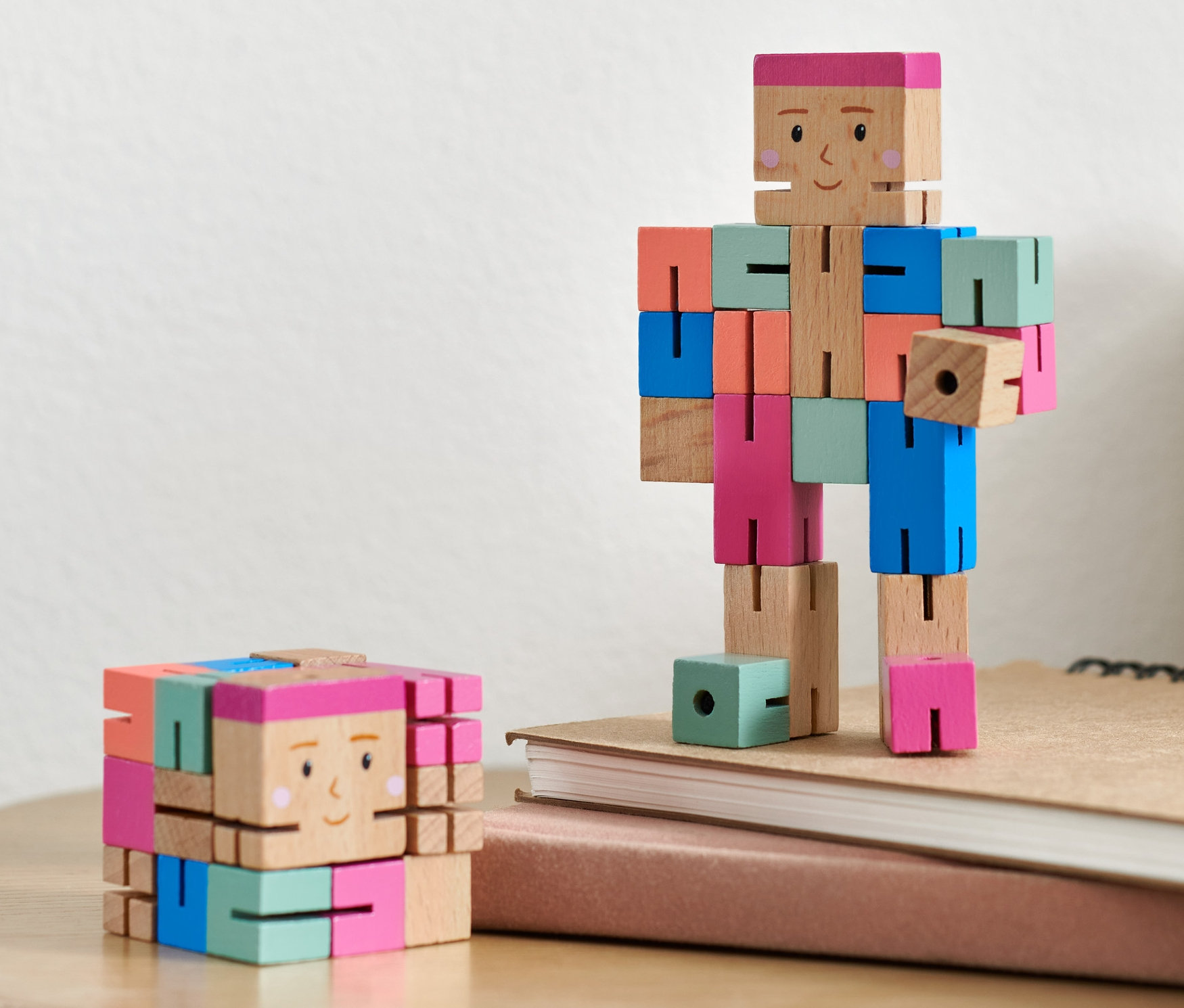 Zwei IQ-Puzzlefiguren stehen auf einem Tisch. Eine ist in Würfelform, die andere in menschlicher Form.