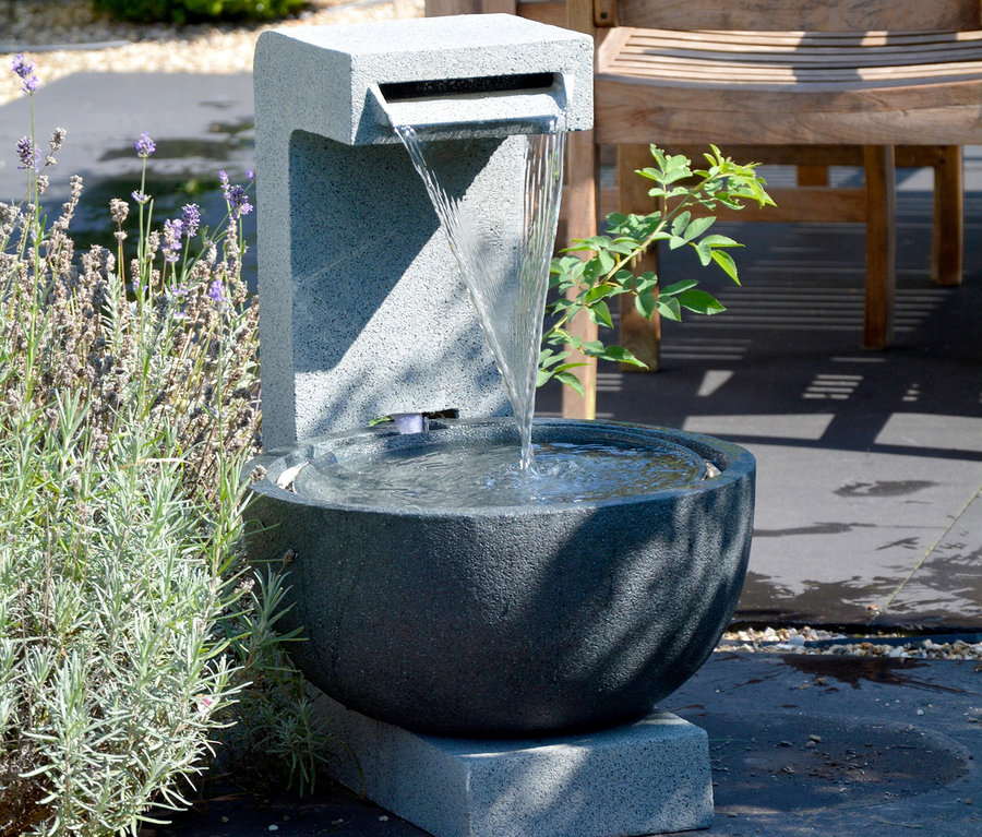 Ein grauer Dobar Gartenbrunnen mit Schale, aus dem Wasser fließt, steht im Freien.