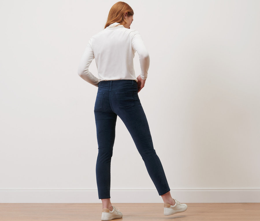 Eine Frau steht mit dem Rücken zur Kamera und trägt eine dunkelblaue Samthose.