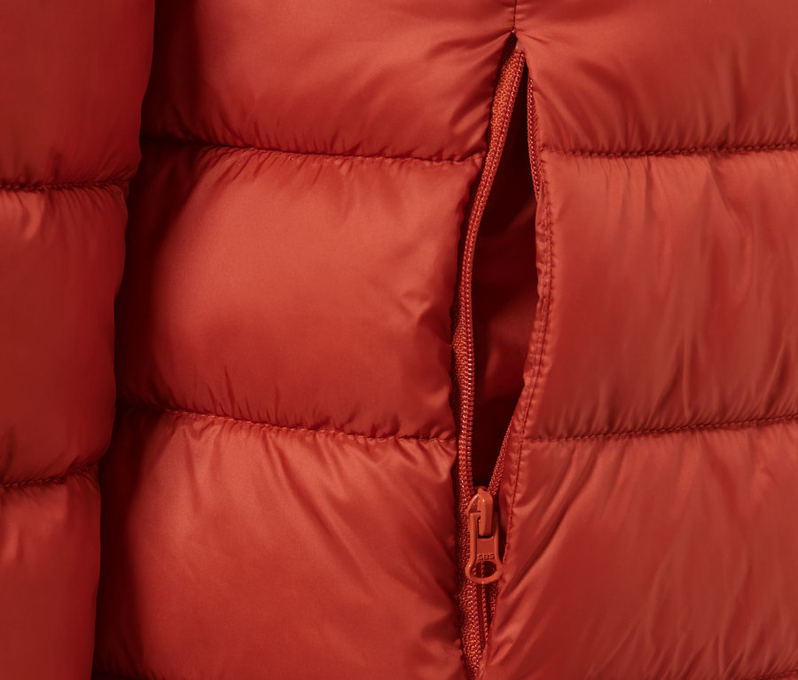Detailansicht einer orangefarbenen Steppjacke mit offenem Reißverschluss.