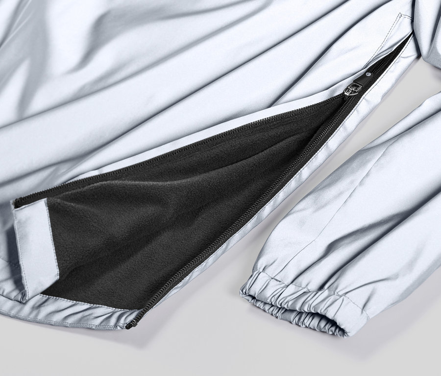 Detailansicht einer reflektierenden Windjacke mit offenem Reißverschluss.