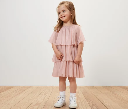 Ein lächelndes Mädchen trägt ein Kinder-Tüllkleid.