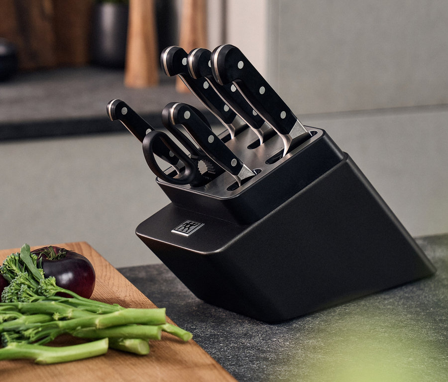 Schwarzer ZWILLING PRO Messerblock mit selbstschärfendem 7-teiligem Messerset und Gemüse auf einer Arbeitsfläche.