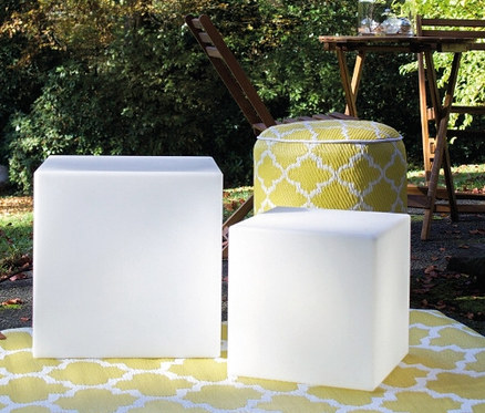 Zwei weiße Solar-Würfel auf einem gelb-weißen Teppich im Freien.