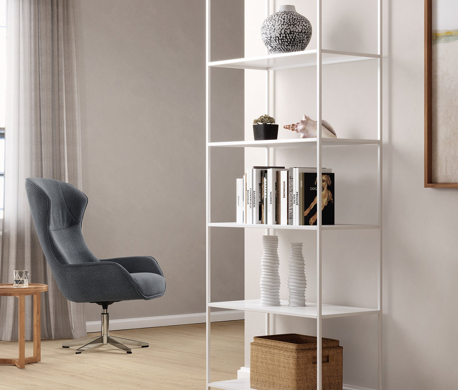 Blauer Sessel mit Drehfunktion neben einem weißen Metallregal. Auf dem Regal stehen Deko-Objekte.