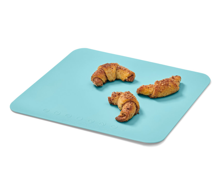 Drei Croissants liegen auf einer blauen Macaron-Backmatte.