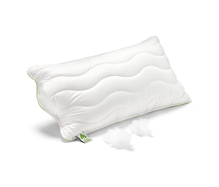 Ein weißes irisette® greenline Kopfkissen Megafil® BIO, ca. 65 x 100 cm, liegt auf einem weißen Hintergrund neben zwei Füllstoffbüscheln.
