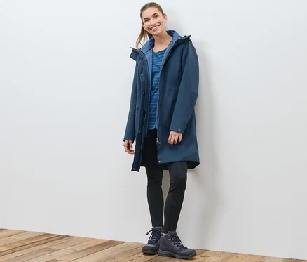 Eine Frau posiert in einem marineblauen 3-in-1-Funktionsmantel mit Weste.