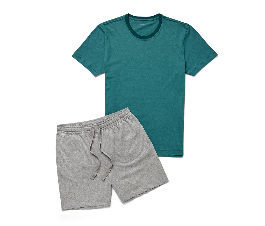 Ein grünes T-Shirt und graue Shorts aus einem Shorty-Pyjama-Set liegen auf einem weißen Hintergrund.