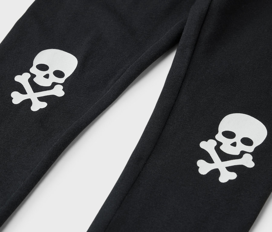 Detailaufnahme einer schwarzen Trainingshose mit weißem Totenkopf und gekreuzten Knochen am Bein.
