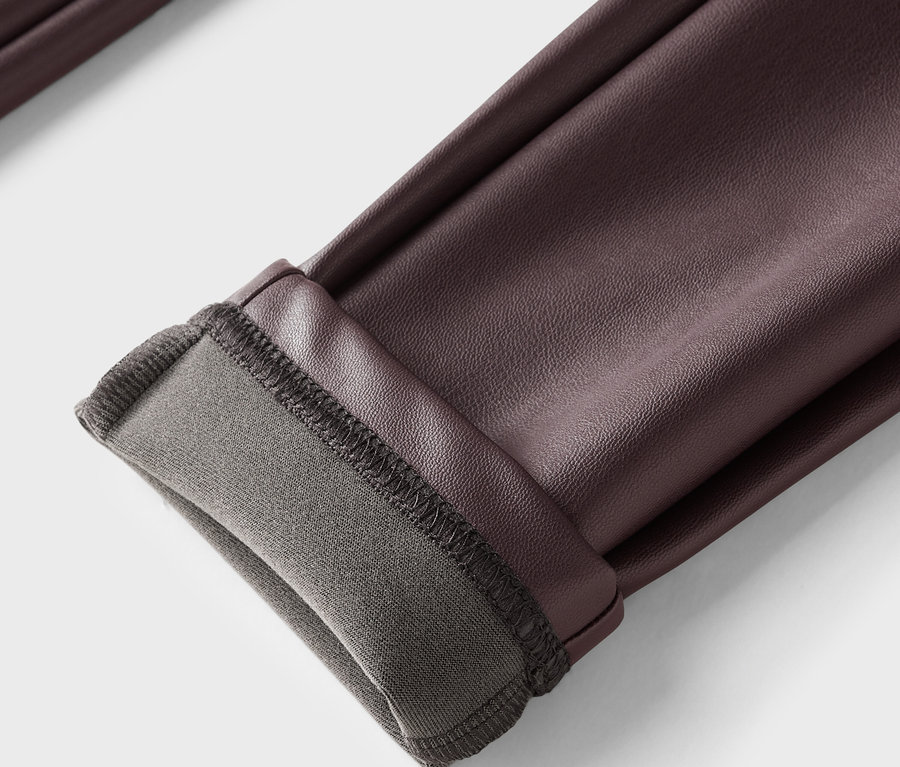 Detailaufnahme einer braunen Lederhose mit umgekrempeltem Saum und grauem Futter.