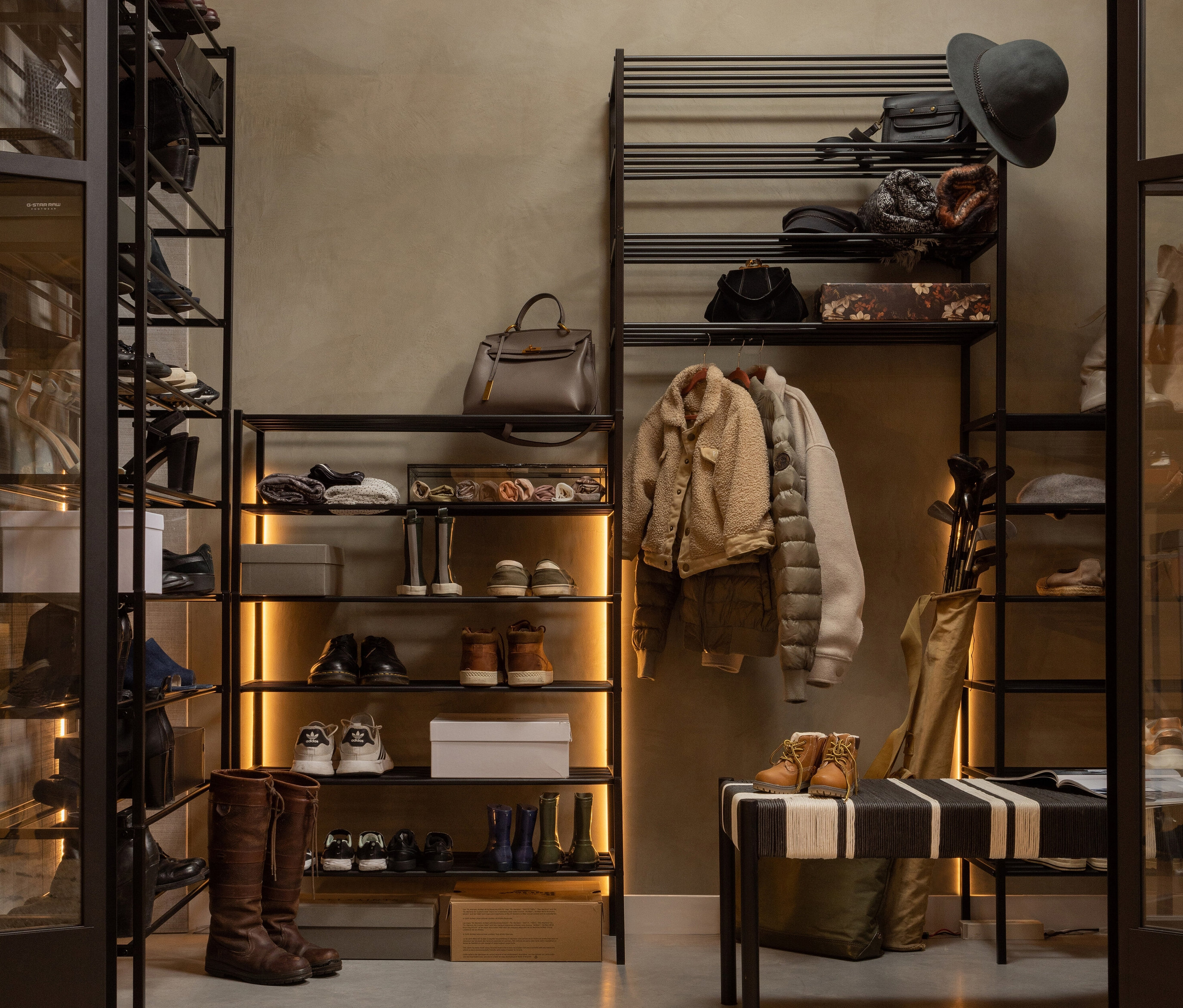 Schuhregale »Ferro« aus Metall in Schwarz mit Schuhen und Kleidung.