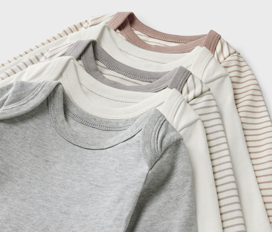 Detailansicht von fünf Baby-Bodys mit Mitwachsfunktion.