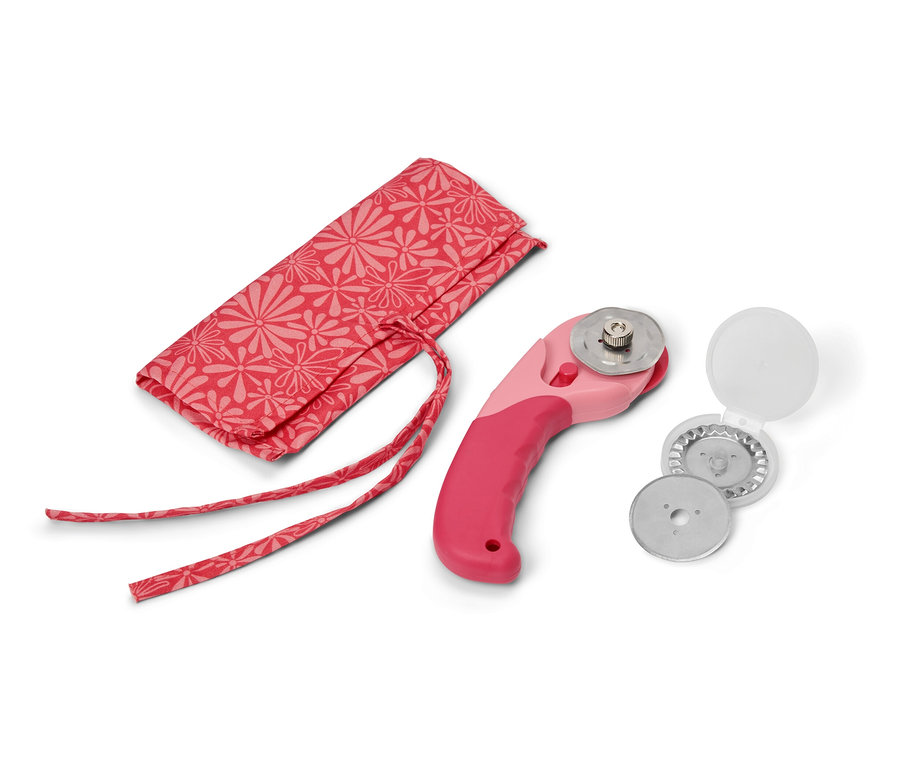 Ein Stoff-Rollschneider neben einer Hülle und Ersatzklingen.