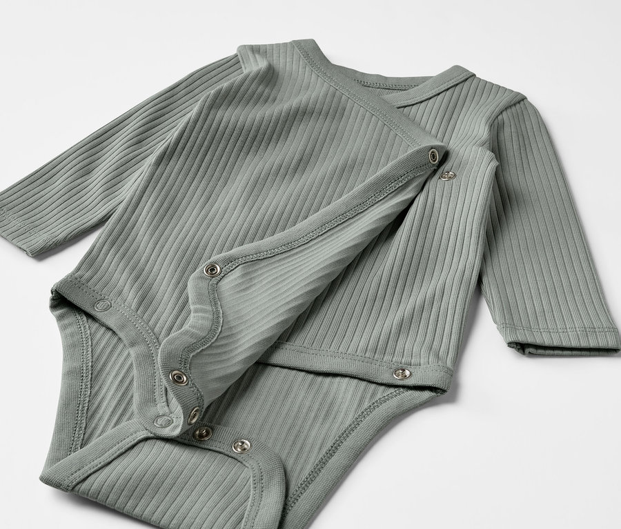 Zwei graugrüne Baby-Ripp-Langarmbodys liegen übereinander.